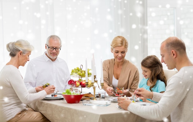 família, feriados, geração, natal e conceito de pessoas - família sorridente jantando em casa