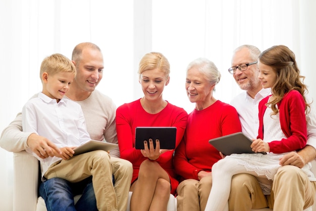 família, feriados, natal, tecnologia e conceito de pessoas - família sorridente com computadores tablet pc sentado no sofá em casa