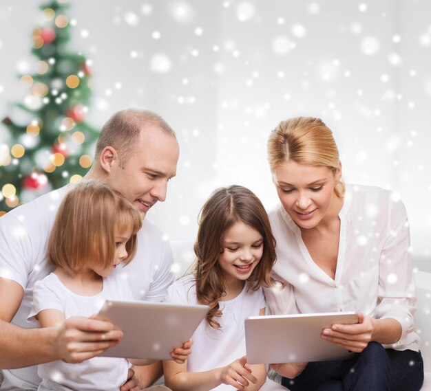 família, feriados, tecnologia e pessoas - sorrindo mãe, pai e filhas com computadores tablet pc em casa