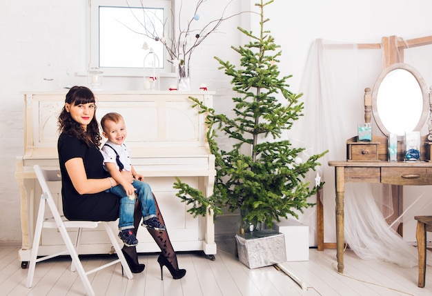 Foto família, férias e conceito de natal - mãe e filho perto da árvore de natal