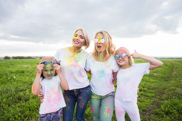 Família, festival de conceito de holi e feriados - feche o retrato de mães e filhas coberto de tinta.