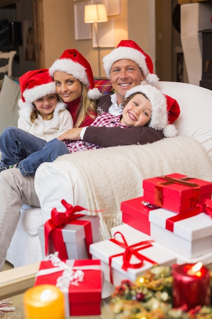 Familia festivo en santa sombrero abrazándose en el sofá