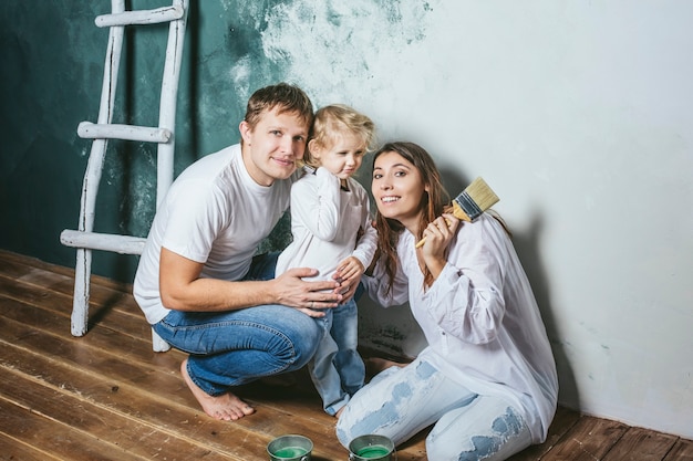 Família, filha feliz com a mãe e o pai fazendo reparos em casa, pintando paredes, junto com amor