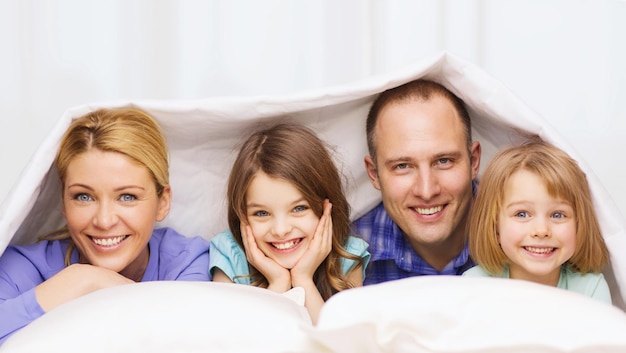 família, filhos e conceito de casa - família feliz com dois filhos debaixo do cobertor em casa