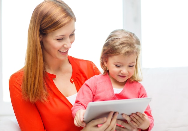 Família, filhos, paternidade, tecnologia e conceito de internet - feliz mãe e filha com computador tablet pc em casa