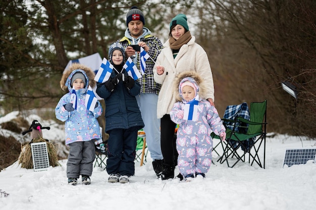 Família finlandesa com bandeiras da Finlândia em um belo dia de inverno nórdico escandinavo