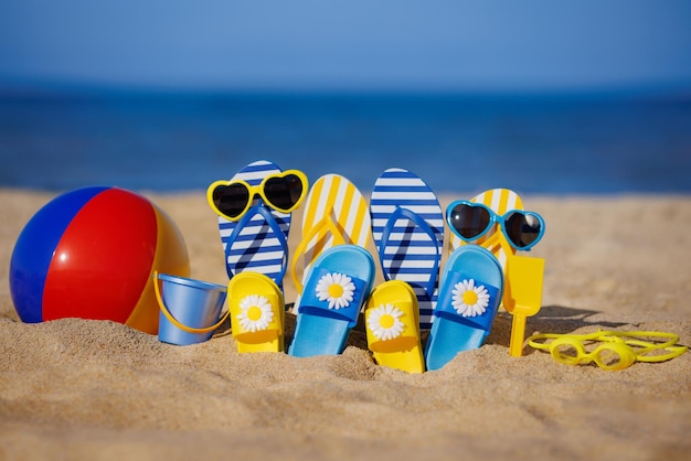 Família flipflops bola de praia e snorkel na areia Conceito de férias de verão