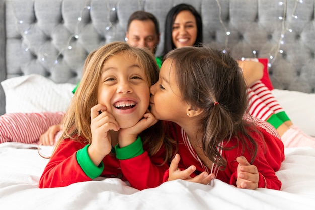 Família fofa deitada na cama no natal