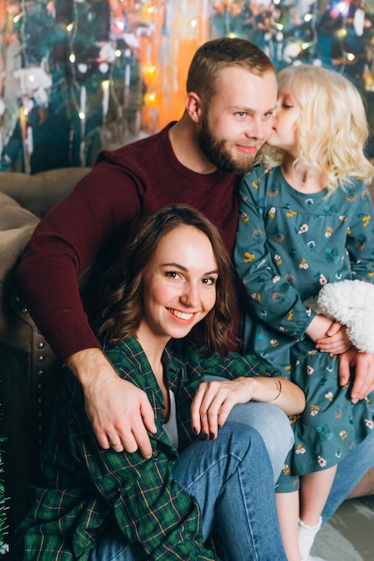 Família fofa mãe, pai e filha posam para a árvore de Natal