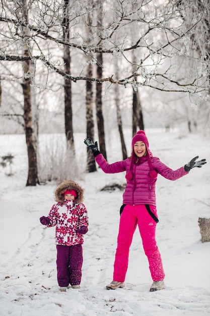 Família fofa se diverte em um parque de inverno mãe e filha brincam no inverno em roupas quentes se divertem abraçando alegrem-se dia da família