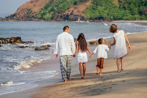 Una familia fuerte camina por la playa desde atrás