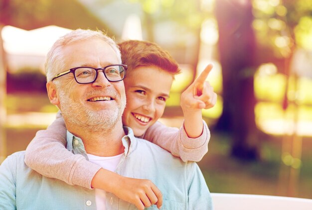 Foto familia, generación, relaciones y concepto de personas - abuelo feliz y nieto señalando con el dedo a algo en el parque de verano