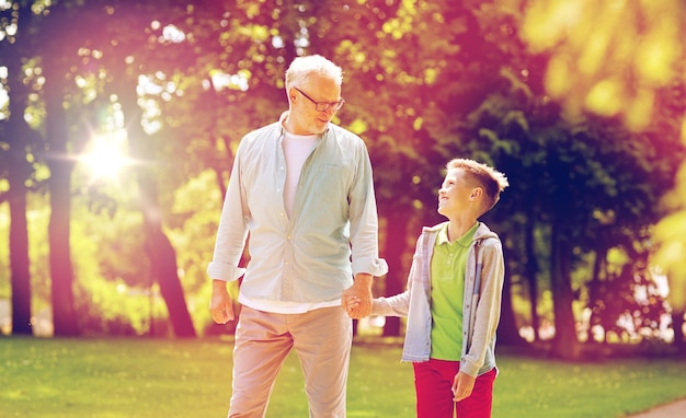 família, geração, comunicação e conceito de pessoas - avô e neto felizes caminhando no parque de verão