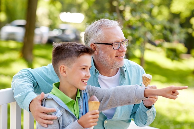 família, geração, comunicação e conceito de pessoas - feliz avô e neto comendo sorvete no parque de verão