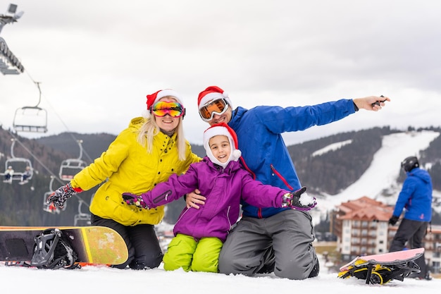 Foto familia con gorros de santa y tablas de snowboard.