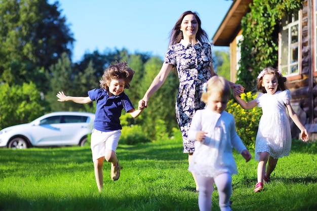 Família grande jovem em uma caminhada de manhã de verão. Linda mãe com filhos está brincando no parque.