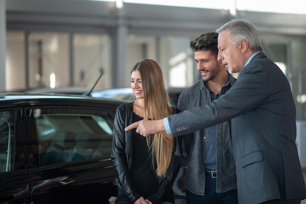 Familia hablando con el vendedor y eligiendo su nuevo coche en una sala de exhibición