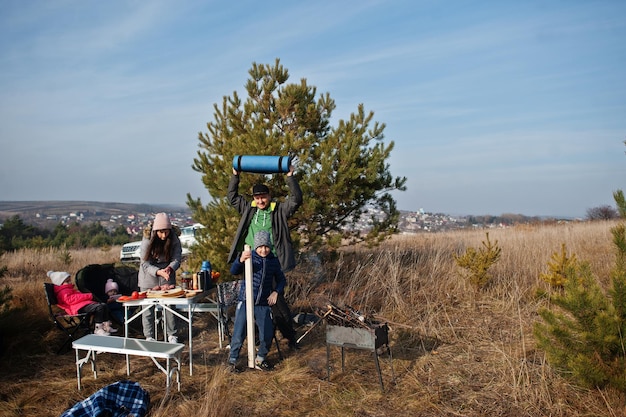 Familia haciendo una barbacoa en una terraza en el bosque de pinos. Día de barbacoa con grill.