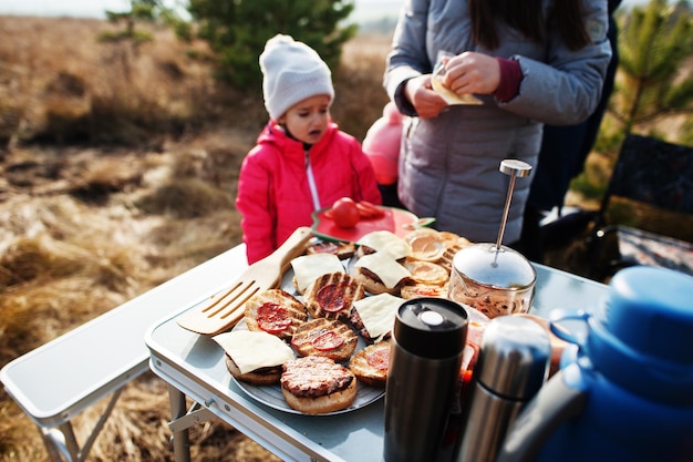 Familia haciendo una barbacoa en una terraza en el bosque de pinos. Día de barbacoa con grill.