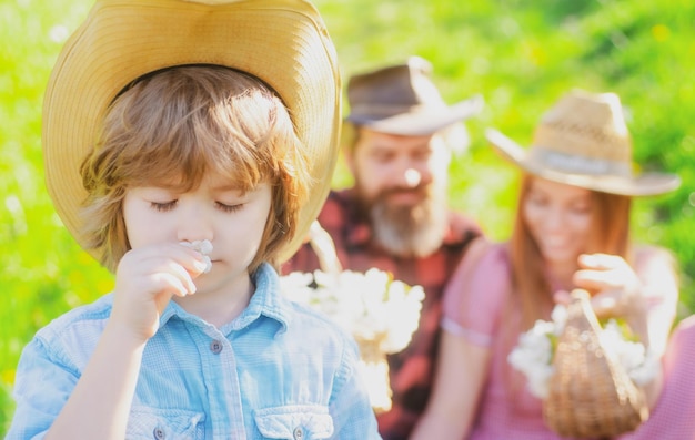 Familia haciendo picnic en el jardín Joven niño sonriente ocio juntos día soleado Boy sniff flower