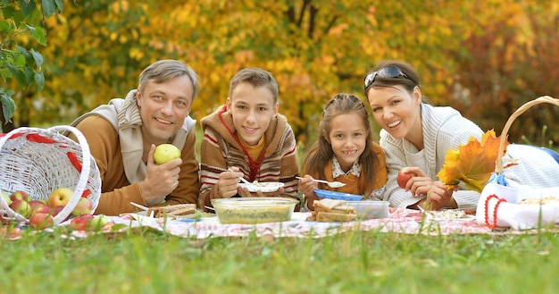 Familia haciendo un picnic en el parque en otoño