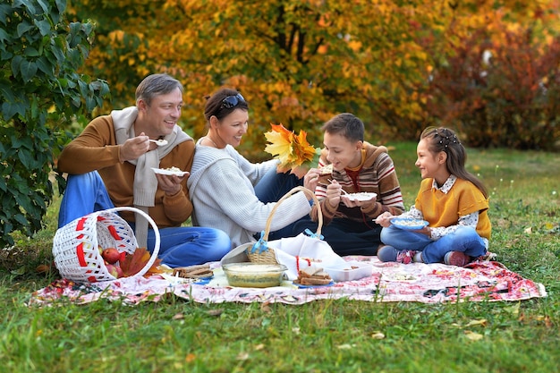 Familia haciendo un picnic en el parque en otoño