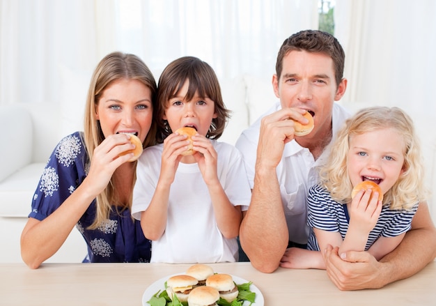 Familia hambrienta comiendo hamburguesas en la sala de estar