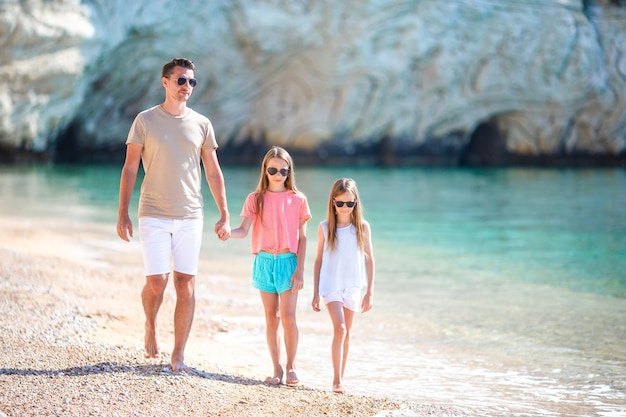 Familia hermosa feliz de papá y niños en la playa blanca