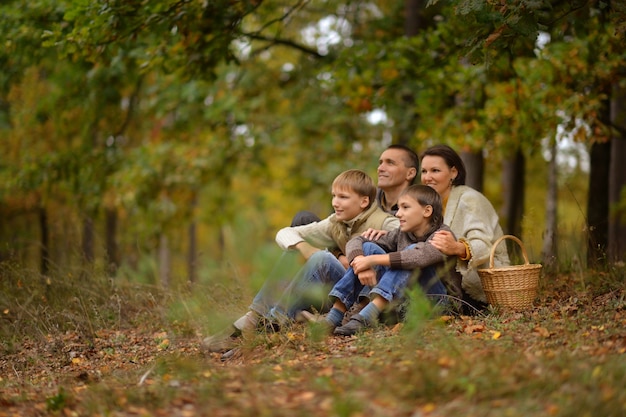 Familia hermosa feliz relajante en el bosque de otoño