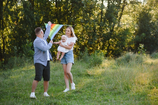 Foto familia hermosa joven con una pequeña hija abrazar, besar y caminar en la naturaleza al atardecer. foto de una familia con un niño pequeño en la naturaleza.