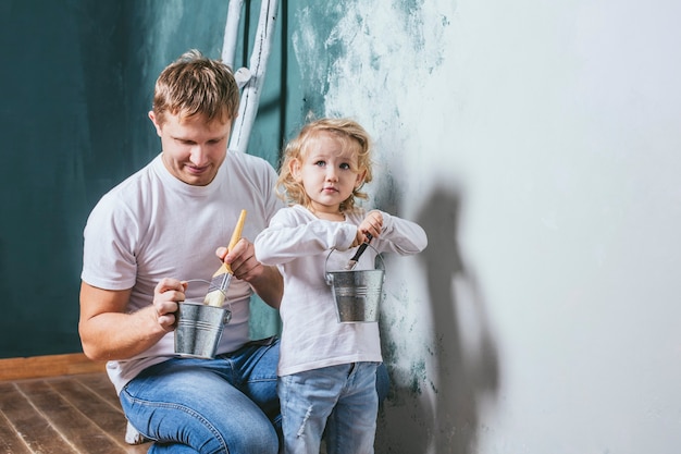 Familia, hija feliz con papá haciendo reparaciones en el hogar, pintar paredes, junto con amor