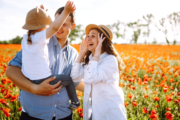 Familia con hijo caminando por el campo de amapolas Madre padre hija pequeña divirtiéndose en el campo de maplas