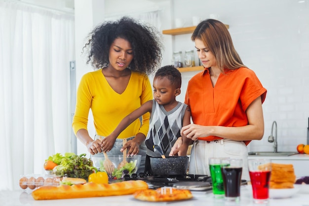Família homossexual ensina filho negro a cozinhar alegremente na cozinha para preparar o jantar Estilo de vida familiar LGBT
