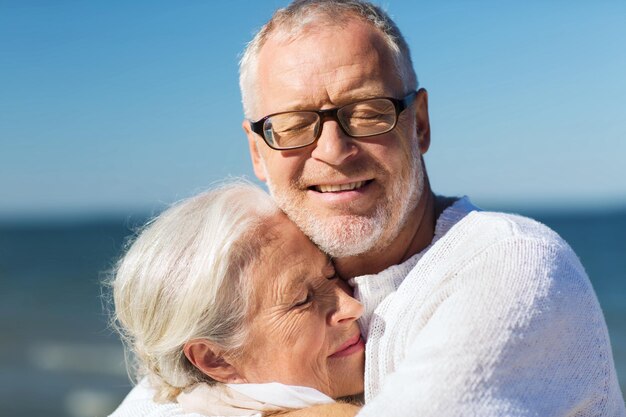 família, idade, viagens, turismo e conceito de pessoas - casal sênior feliz abraçando na praia de verão