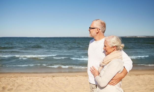 família, idade, viagens, turismo e conceito de pessoas - casal sênior feliz caminhando pela praia de verão