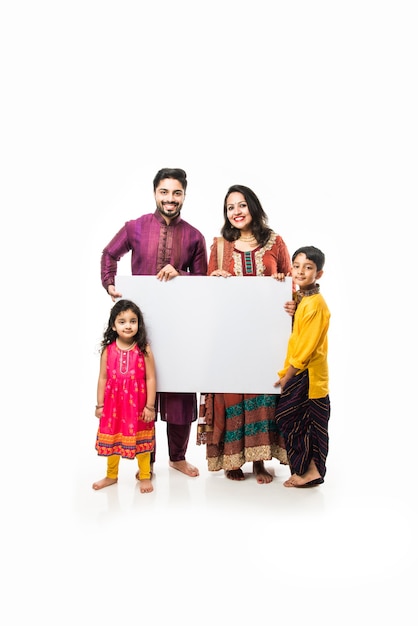 Familia india celebrando Diwali mientras sostiene una pizarra en blanco o un cartel. De pie aislado sobre fondo blanco y mirando a la cámara