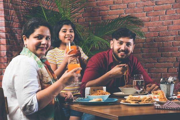 Familia india comiendo en la mesa de comedor en casa o en un restaurante comiendo juntos