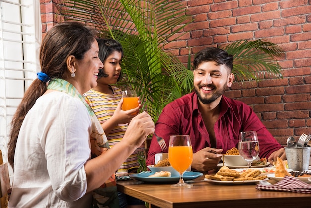 Familia india comiendo en la mesa de comedor en casa o en un restaurante comiendo juntos