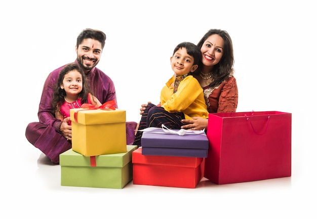 Família indiana celebrando diwali ou deepavali com roupas tradicionais enquanto está sentado isolado sobre um fundo branco com caixas de presente e lâmpada em thali