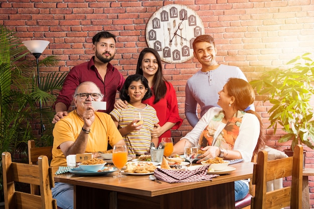 Família indiana comendo comida na mesa de jantar em casa ou restaurante fazendo as refeições juntos