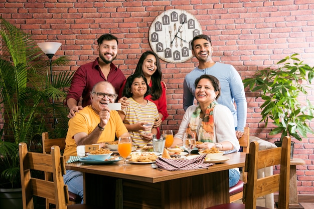 Família indiana comendo comida na mesa de jantar em casa ou restaurante fazendo as refeições juntos