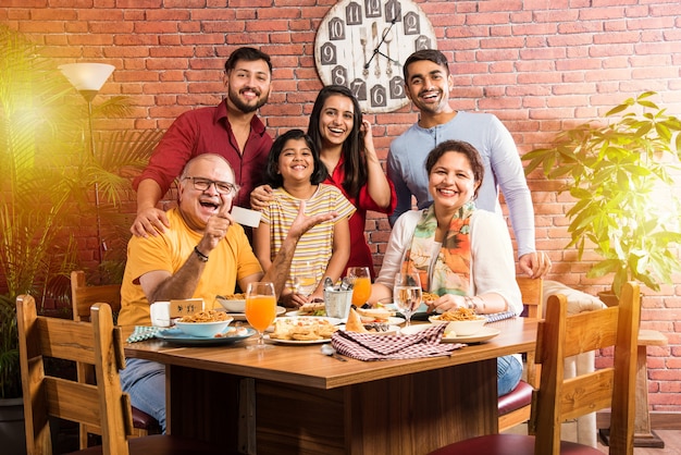 Família indiana comendo comida na mesa de jantar em casa ou restaurante fazendo as refeições juntos