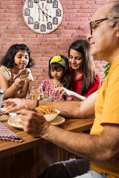 Família indiana comendo comida na mesa de jantar em casa ou restaurante fazendo as refeições juntos