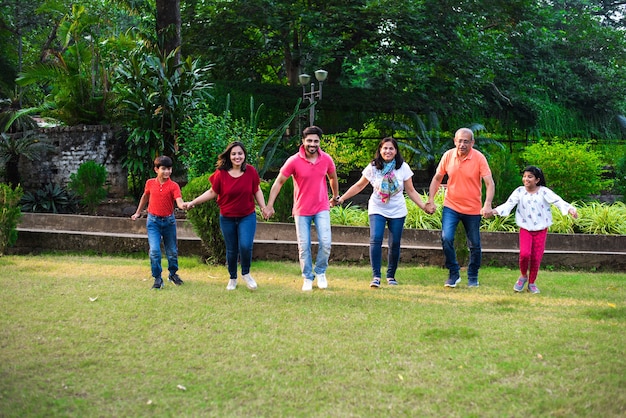 Família indiana desfrutando piquenique - Multi geração de família asiática caminhando ou jogando perseguindo o jogo no parque que faz a corrente humana. foco seletivo