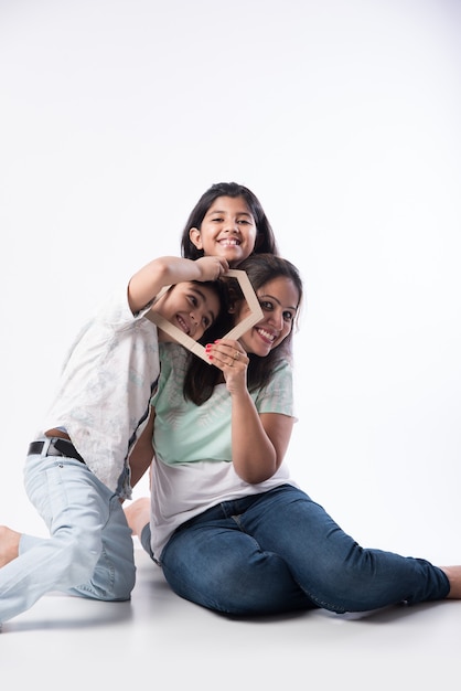 Família indiana pai, mãe, filho e filha segurando um modelo 3d de casa em papel - real istate concept na índia