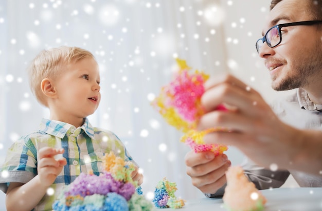 familia, infancia, creatividad, actividad y concepto de personas - padre feliz y hijo pequeño jugando con bola de arcilla en casa sobre la nieve