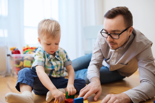 família, infância, criatividade, atividade e conceito de pessoas - pai feliz e filho brincando com blocos de brinquedo em casa