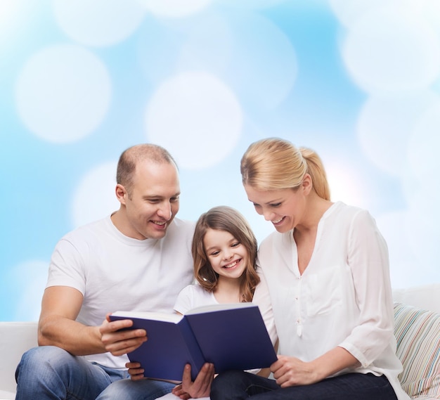 família, infância, feriados e pessoas - sorrindo mãe, pai e menina lendo livro sobre fundo de luzes azuis