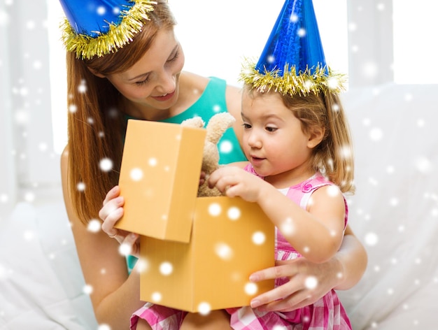 família, infância, férias e conceito de pessoas - feliz mãe e filha em chapéus de festa azuis com caixa de presente