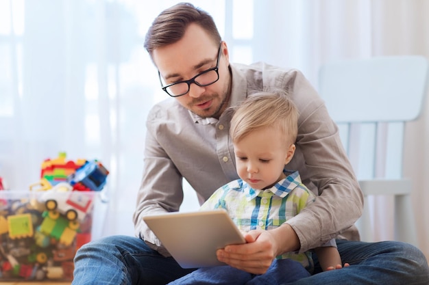 família, infância, paternidade, tecnologia e conceito de pessoas - feliz pai e filho com computador tablet pc jogando em casa